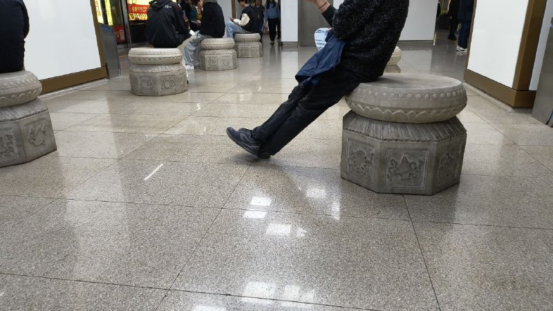 地铁站里每个石墩子上都坐着一个人类，像是在玩什么真人象棋